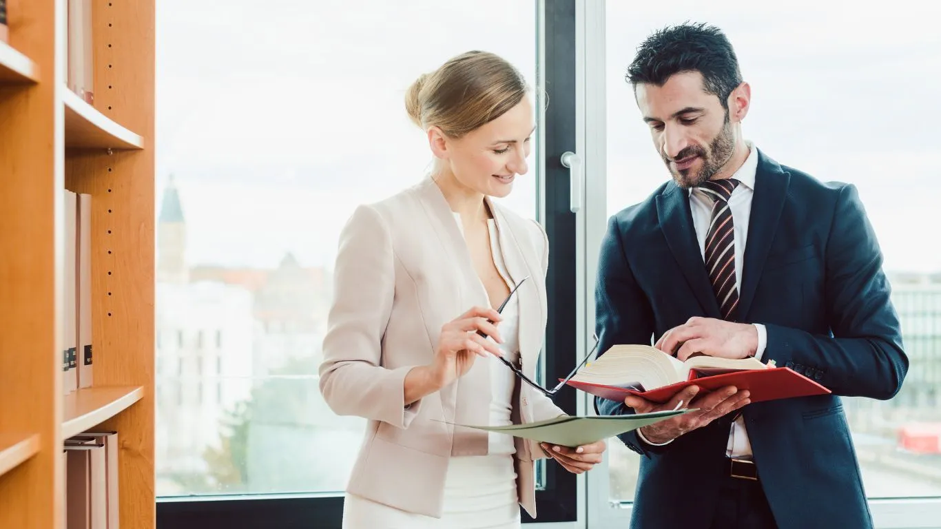 Professional business consultants reviewing EU Pay Transparency Directive compliance documentation and strategic planning materials in a modern office setting