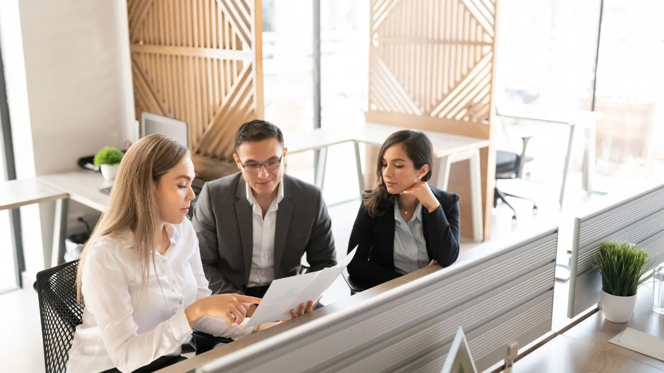 Business professionals collaborating on EU Pay Transparency Directive compliance strategy in a modern office environment, reviewing documentation and planning proactive implementation