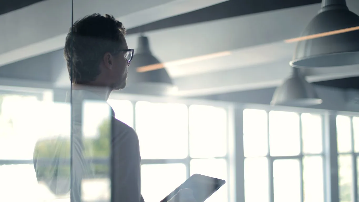 Professional strategist overlooking a modern office environment, representing Acevo's forward-thinking approach to business transformation and strategic consulting